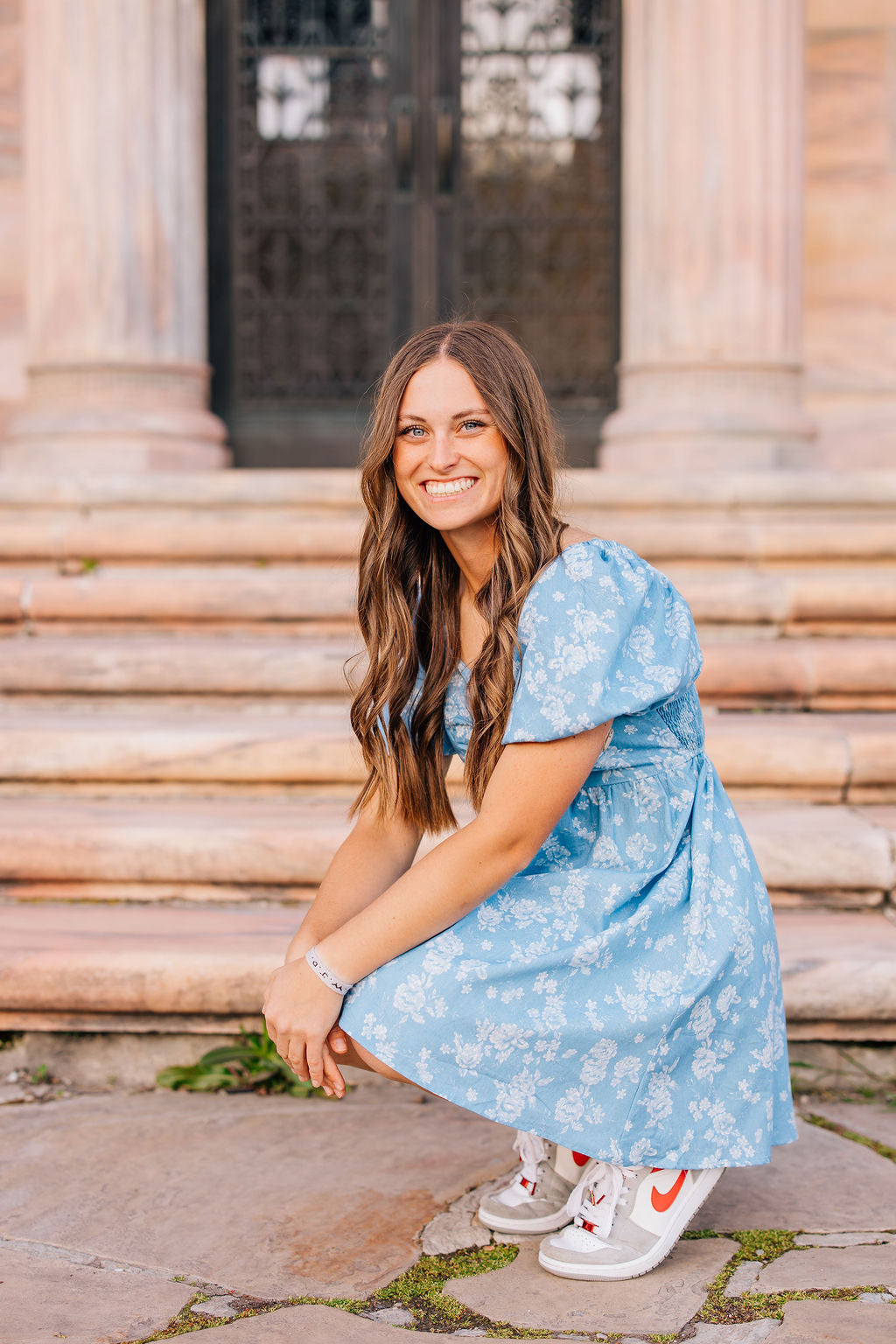 Woman in a blue floral dress sitting on steps outdoors